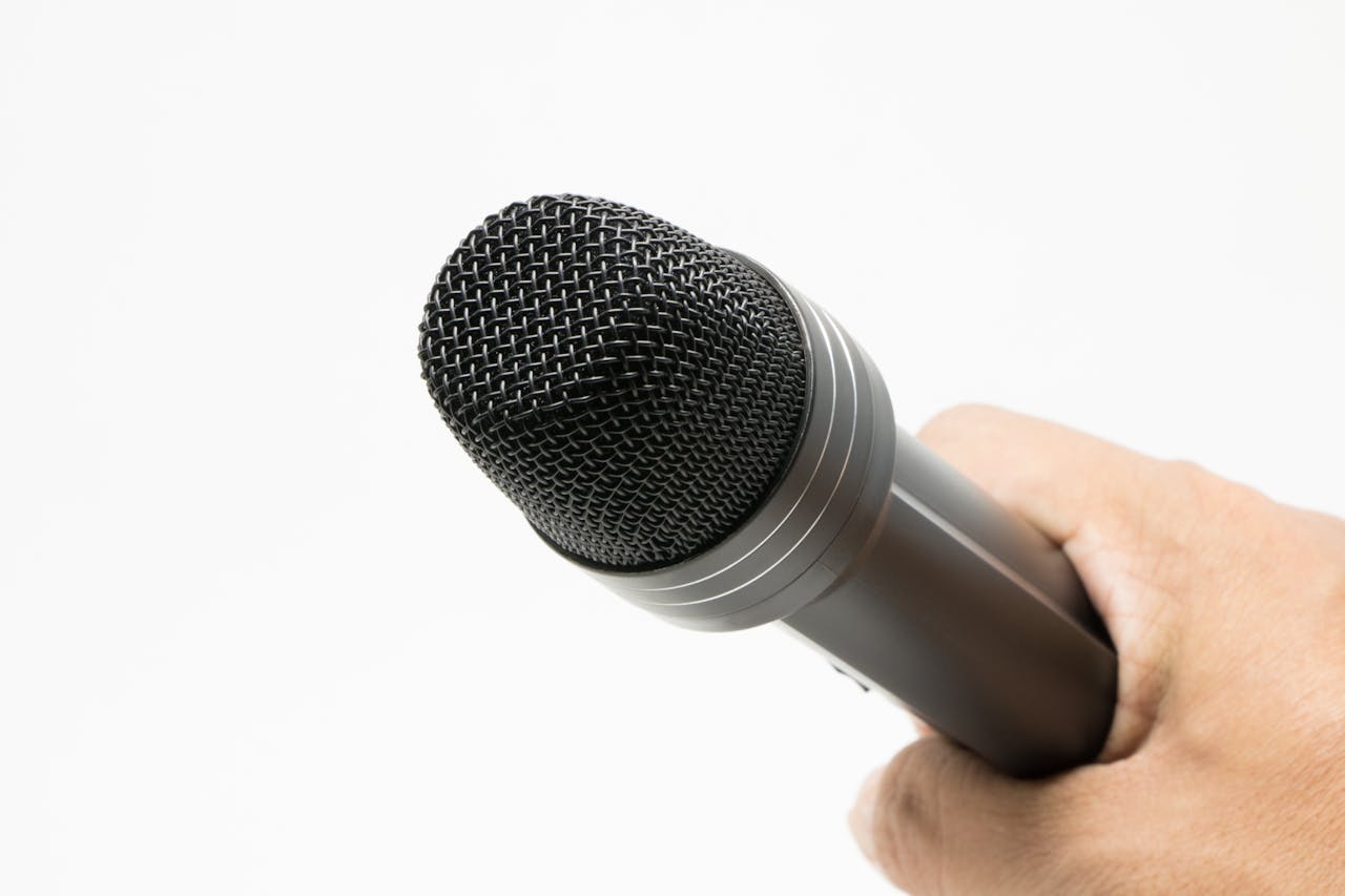 Close-up image of a microphone held in hand against a white background.